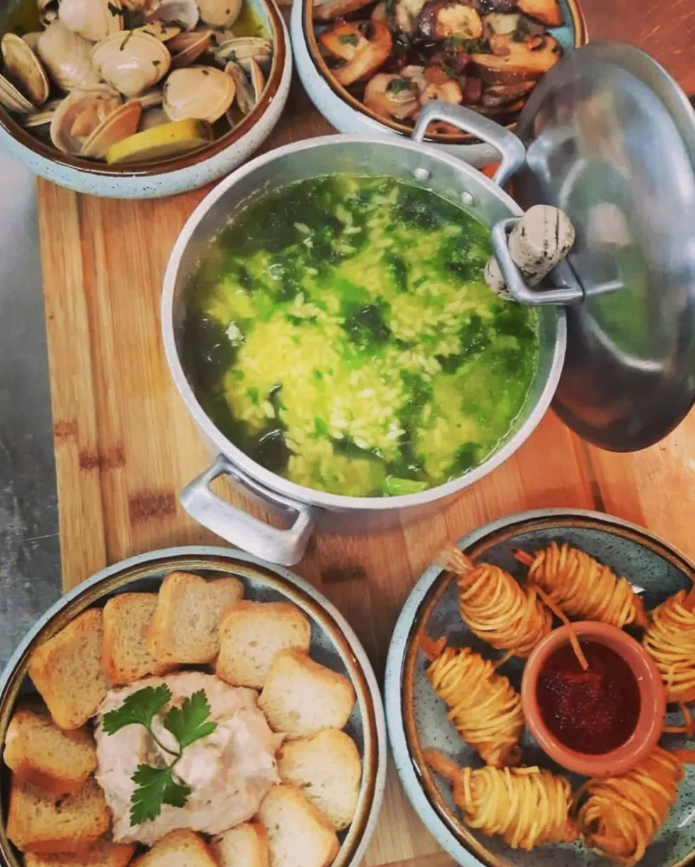 Mesa de tapas com amêijoas, cogumelos, patê, gambas em fio de batata e arroz de grelos
